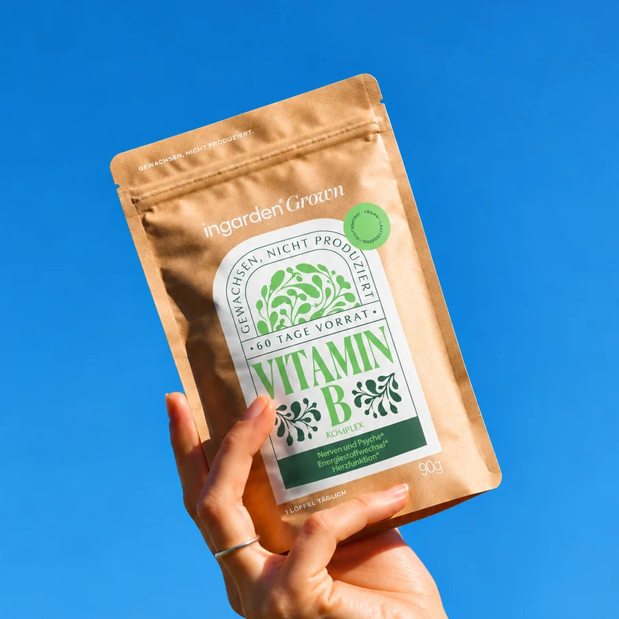 Hand hält ingarden grown Vitamin B-Komplex Beutel vor blauem Himmel