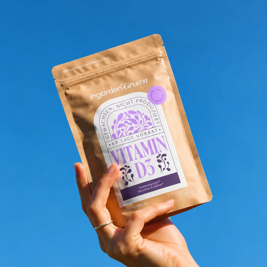 Hand hält ingarden grown Vitamin D3 Beutel vor blauem Himmel